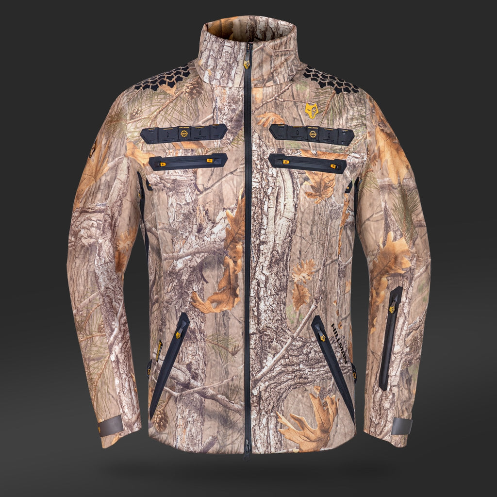 Die 6OL Winter Jagdjacke von HILLMAN GEAR ist eine Camouflage-Jagdjacke mit Baumrinden- und Blattmuster auf dunklem Stoff. Sie hat schwarze Reißverschlüsse an der Brust und an den Taschen, einen hohen Kragen und ein dezentes Logo. Diese wasserdichte Jagdjacke verwendet innovative Materialien für verbesserte Haltbarkeit.