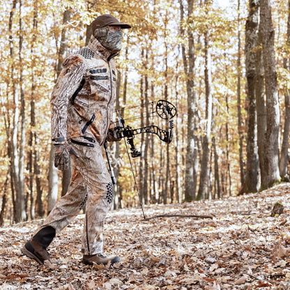 Ein Jäger, der eine Hillman 6OL Winter Jagdhose trägt – eine wasserdichte, dornenfeste Trekkinghose – manövriert mit seinem Compoundbogen im Anschlag behutsam durch den Wald. Gefallene Blätter bedecken den Boden, während hohe Bäume im sanften goldenen Sonnenlicht leuchtende Herbstfarben zeigen.